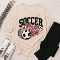 Cream crewneck long sleeve Soccer Mom graphic tee featuring pink lettering, soccer ball, goal and leopard print accents.