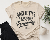 Beige graphic T-shirt with black vintage-style lettering reading Anxiety? Oh, You Mean My Daily Personality Trait.