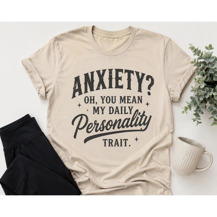 Beige graphic T-shirt with black vintage-style lettering reading Anxiety? Oh, You Mean My Daily Personality Trait.