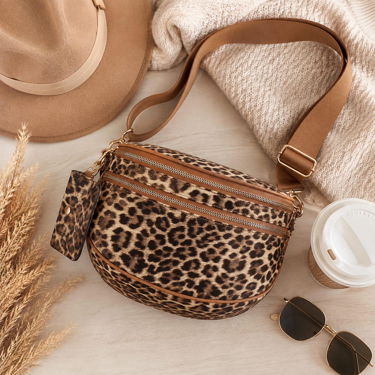 Leopard print crossbody handbag with brown adjustable strap, gold-tone hardware, multiple zipper compartments and matching mini pouch.