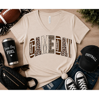 Neutral Game Day graphic t-shirt featuring varsity-style lettering with football, leopard, gingham, polka dot, and striped patterns, styled with jeans and football accessories for fall football season.