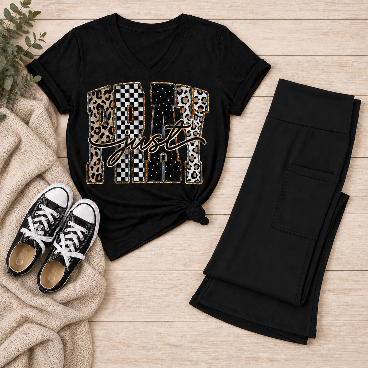 Black Just Pray V-neck graphic T-shirt with leopard, checkerboard, cow-print, star, and gold accents styled with black pocket leggings and sneakers.