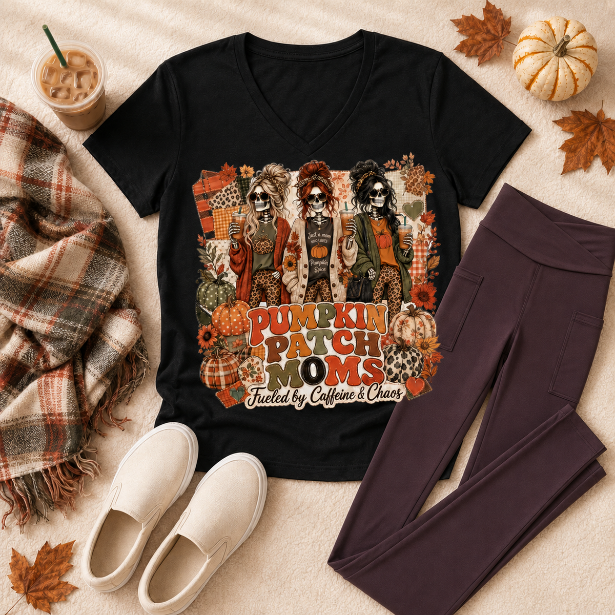 Black Pumpkin Patch Moms graphic T-shirt featuring three skeleton moms, colorful pumpkins, fall patterns, and Fueled by Caffeine and Chaos text.
