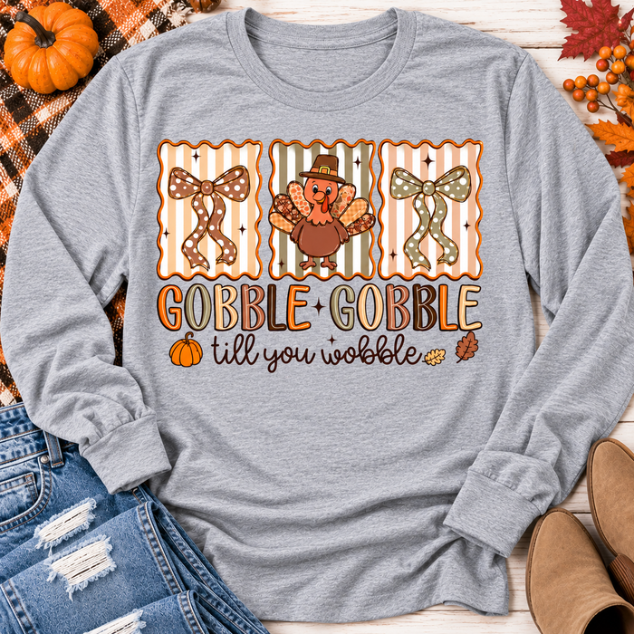 Gobble Gobble Till You Wobble Thanksgiving graphic apparel featuring a cute turkey, polka dot bows, retro fall colors, pumpkins and autumn leaves.