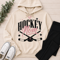Cream Hockey Mom graphic hoodie featuring a black and pink hockey design with crossed sticks, puck, stars and heart details.