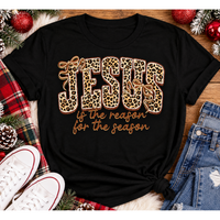Jesus Is the Reason for the Season Christmas graphic shirt featuring bold leopard print JESUS lettering, decorative gold bows, and gold script. Faith-inspired holiday apparel available in red and black with four style options.