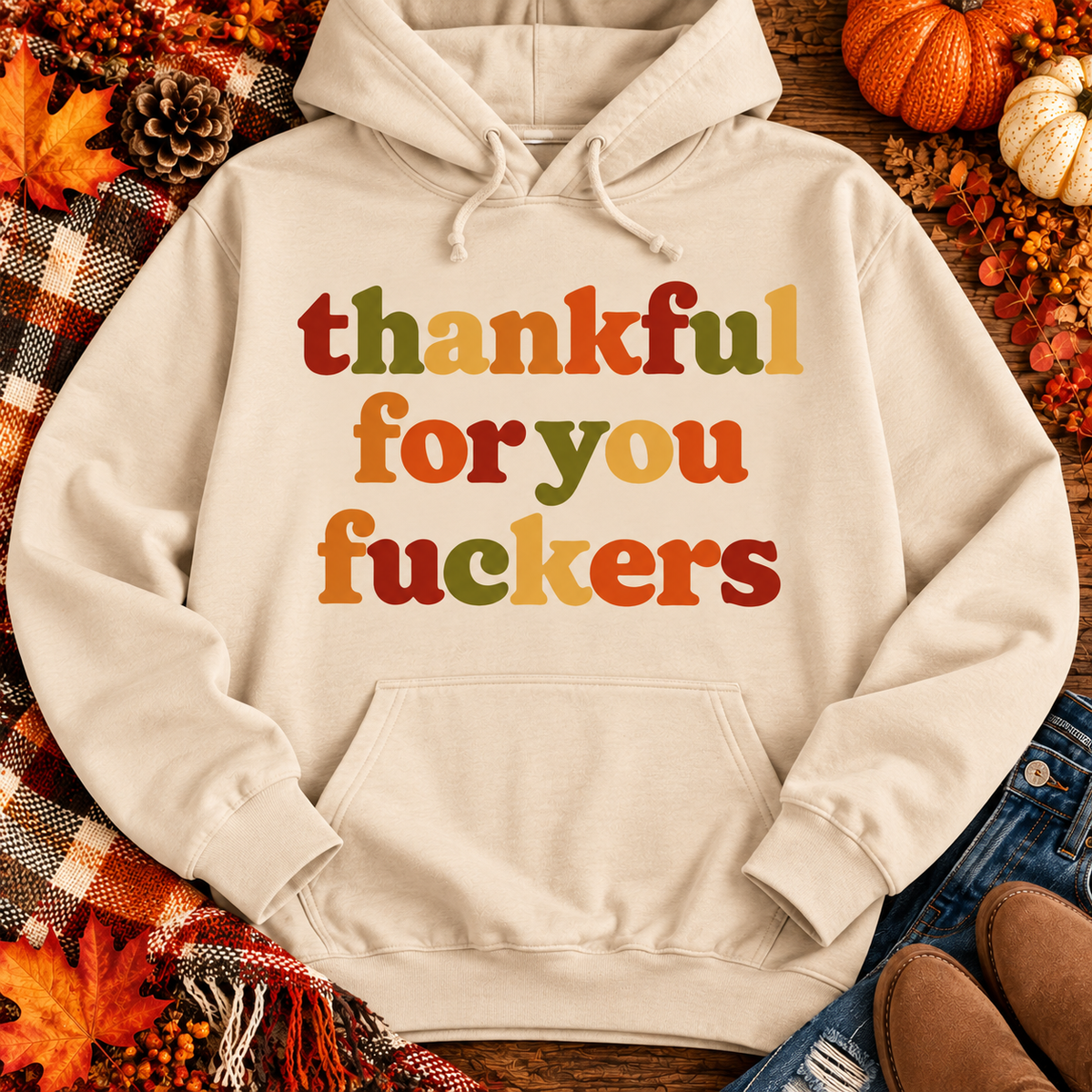 Funny Thankful for You Fuckers Thanksgiving graphic tee featuring bold retro lettering in burnt orange, mustard yellow, olive green, and rust red. Women's fall-inspired short sleeve crewneck shirt available in beige and brown, perfect for Thanksgiving and Friendsgiving.