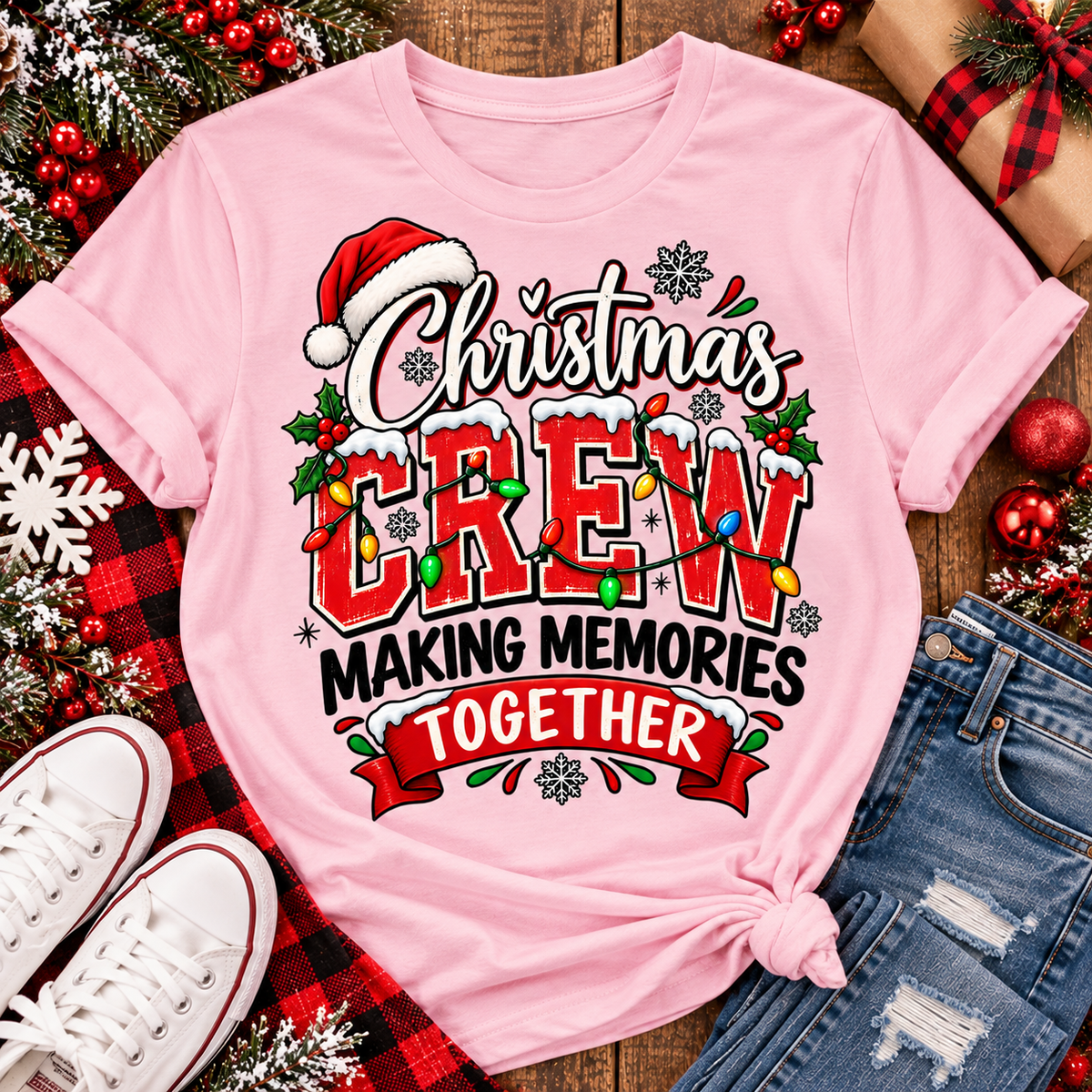 Christmas Crew Making Memories Together graphic on a pink crewneck T-shirt, featuring red lettering, colorful Christmas lights, a Santa hat, holly, and snowflakes.