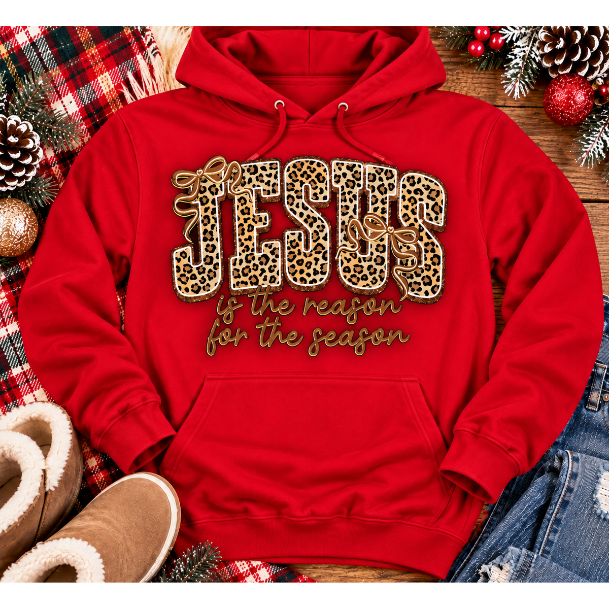 Jesus Is the Reason for the Season Christmas graphic shirt featuring bold leopard print JESUS lettering, decorative gold bows, and gold script. Faith-inspired holiday apparel available in red and black with four style options.
