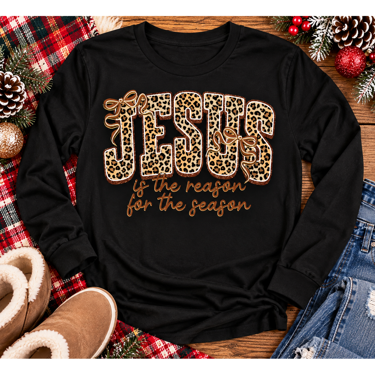 Jesus Is the Reason for the Season Christmas graphic shirt featuring bold leopard print JESUS lettering, decorative gold bows, and gold script. Faith-inspired holiday apparel available in red and black with four style options.