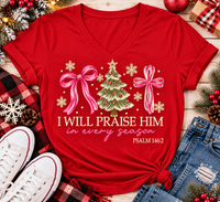 Christian Christmas shirt featuring I Will Praise Him in Every Season Psalm 146:2 graphic with pink bows, decorated Christmas tree, and cream snowflakes.