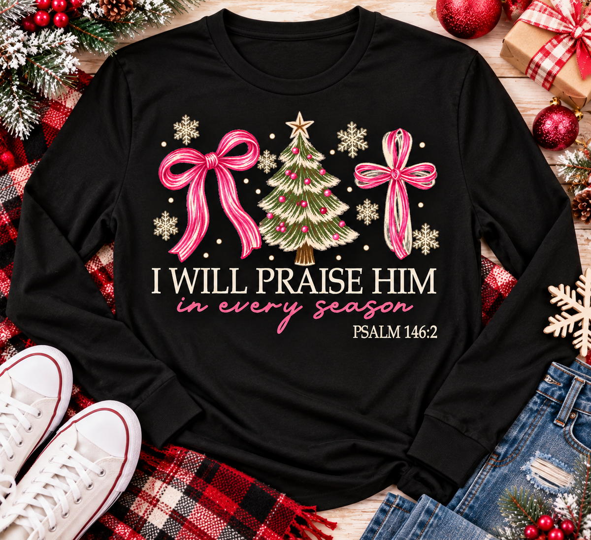 Christian Christmas shirt featuring I Will Praise Him in Every Season Psalm 146:2 graphic with pink bows, decorated Christmas tree, and cream snowflakes.