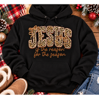 Jesus Is the Reason for the Season Christmas graphic shirt featuring bold leopard print JESUS lettering, decorative gold bows, and gold script. Faith-inspired holiday apparel available in red and black with four style options.