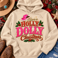 Have a Holly Dolly Christmas western graphic shirt featuring pink and red glitter-inspired lettering, a festive pink cowgirl hat, gold accents, and Christmas holly berries. Available in beige and pink in short sleeve crewneck, V-neck, long sleeve crewneck, and hoodie styles.