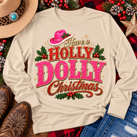 Have a Holly Dolly Christmas western graphic shirt featuring pink and red glitter-inspired lettering, a festive pink cowgirl hat, gold accents, and Christmas holly berries. Available in beige and pink in short sleeve crewneck, V-neck, long sleeve crewneck, and hoodie styles.