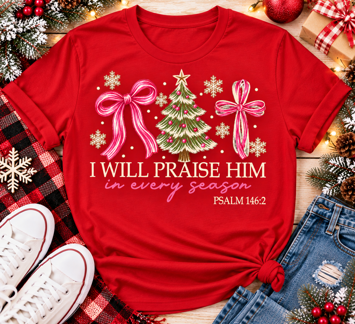 Christian Christmas shirt featuring I Will Praise Him in Every Season Psalm 146:2 graphic with pink bows, decorated Christmas tree, and cream snowflakes.