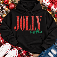 Jolly Ish Christmas graphic shirt featuring large distressed red JOLLY lettering with green handwritten ish script. Funny vintage-inspired holiday apparel available in pink and black, offered in short sleeve crewneck, V-neck, long sleeve and hoodie styles.