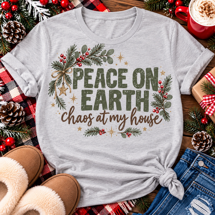 Peace on Earth Chaos at My House funny Christmas graphic apparel featuring distressed olive green lettering, rustic pine greenery, red berries and gold stars, available in sand and sport grey in short sleeve crewneck tees, V-neck tees, sweatshirts and hoodies.