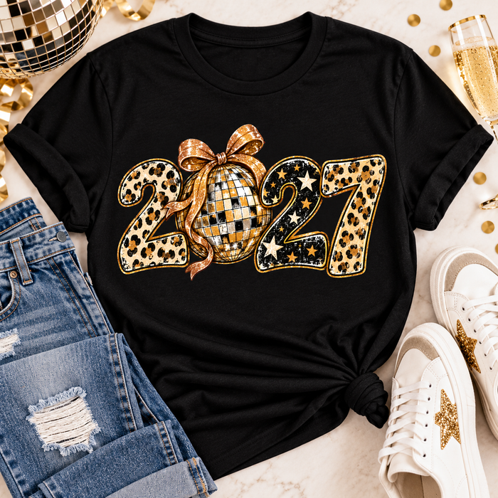 Black 2027 New Year's graphic apparel featuring leopard print numbers, a gold disco ball with an oversized glittery bow, black and gold stars, and sparkling accents. Available in crewneck tee, V-neck tee, sweatshirt, and hoodie styles.
