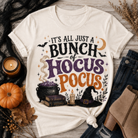 Beige Halloween graphic tee with It’s All Just a Bunch of Hocus Pocus lettering, cauldron, spell books, witch hat and bats.