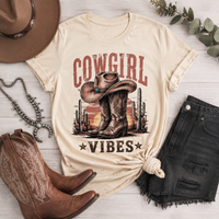 Cowgirl Vibes western graphic apparel featuring cowboy boots, cowgirl hat, cacti and desert sunset design