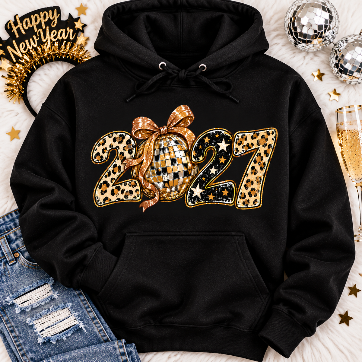 Black 2027 New Year's graphic apparel featuring leopard print numbers, a gold disco ball with an oversized glittery bow, black and gold stars, and sparkling accents. Available in crewneck tee, V-neck tee, sweatshirt, and hoodie styles.