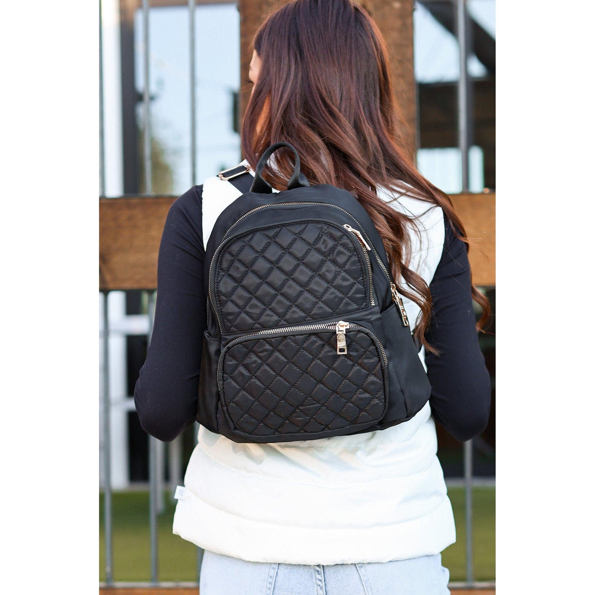black quilted backpack with gold zipper detail worn by woman stylish everyday backpack